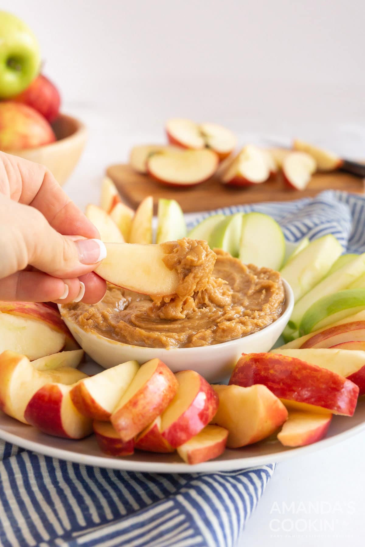 person dipping apple slice in peanut butter apple dip