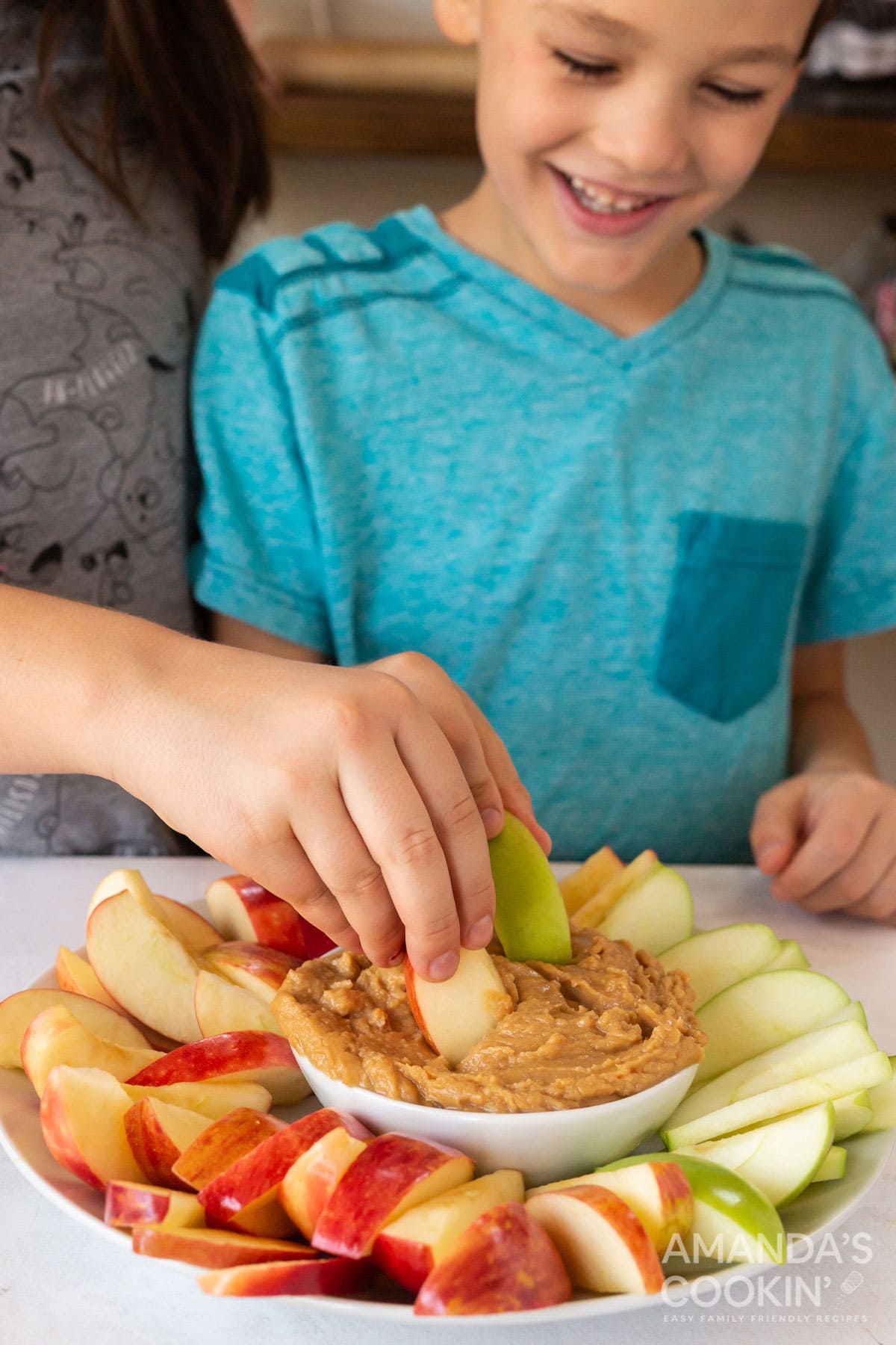 kids dipping apple slices into peanut butter fruit dip