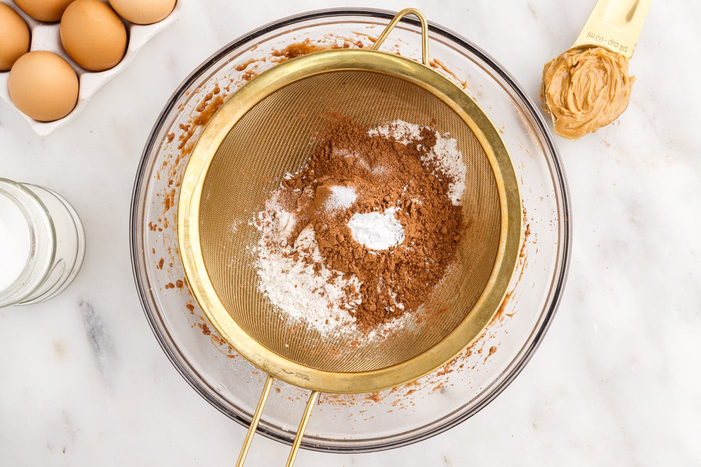 sifting brownie dry ingredients in a bowl