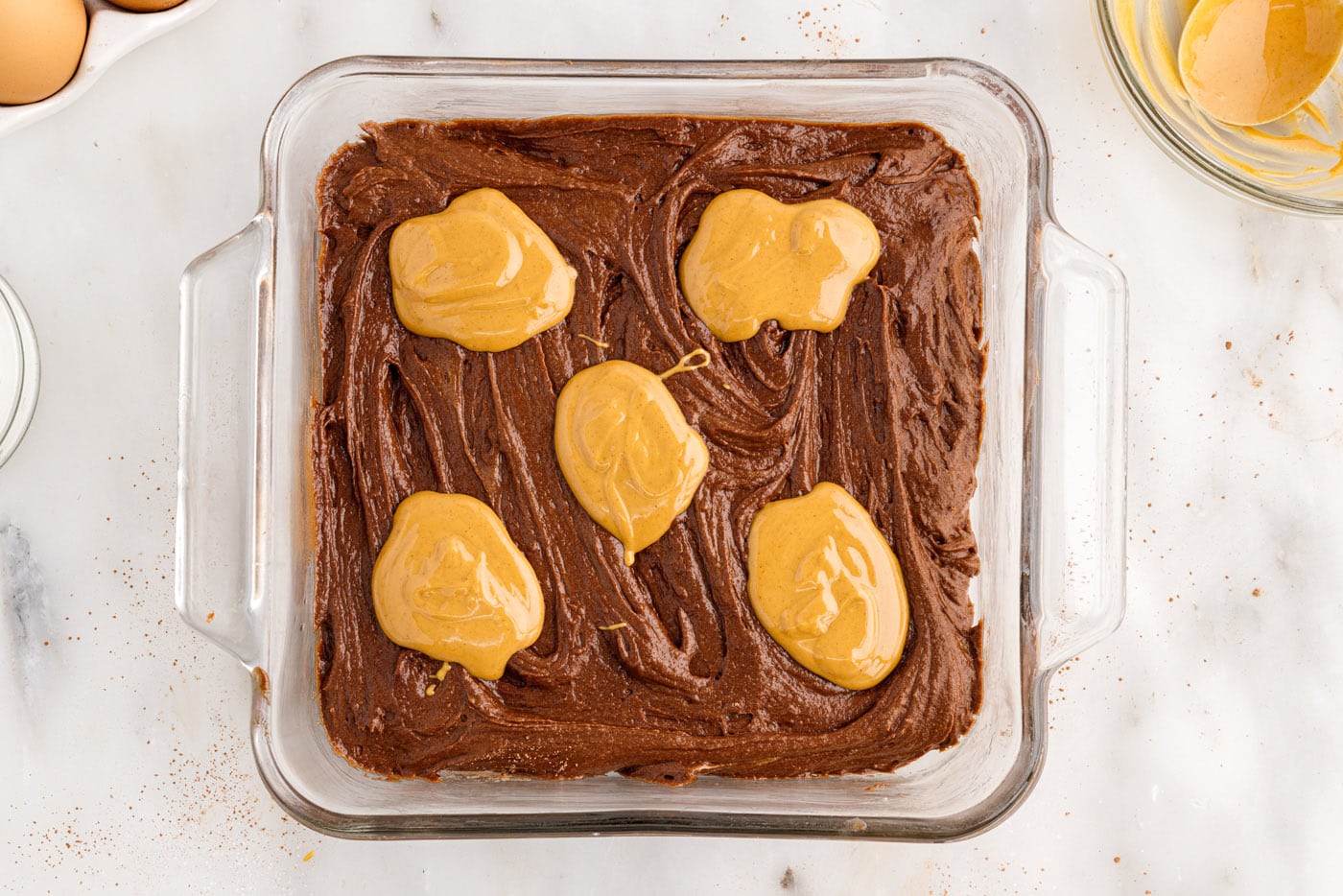 dollops of melted peanut butter on top of brownie batter