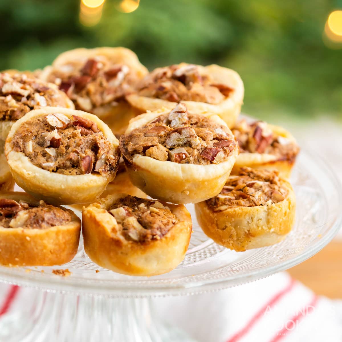 pecan tassies piled on a cake plate