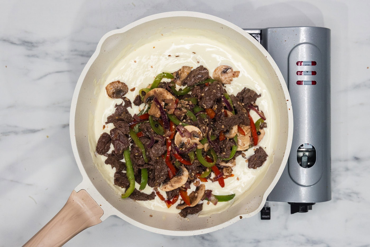 steak and veggie mixture added to skillet of heavy cream and cheese sauce