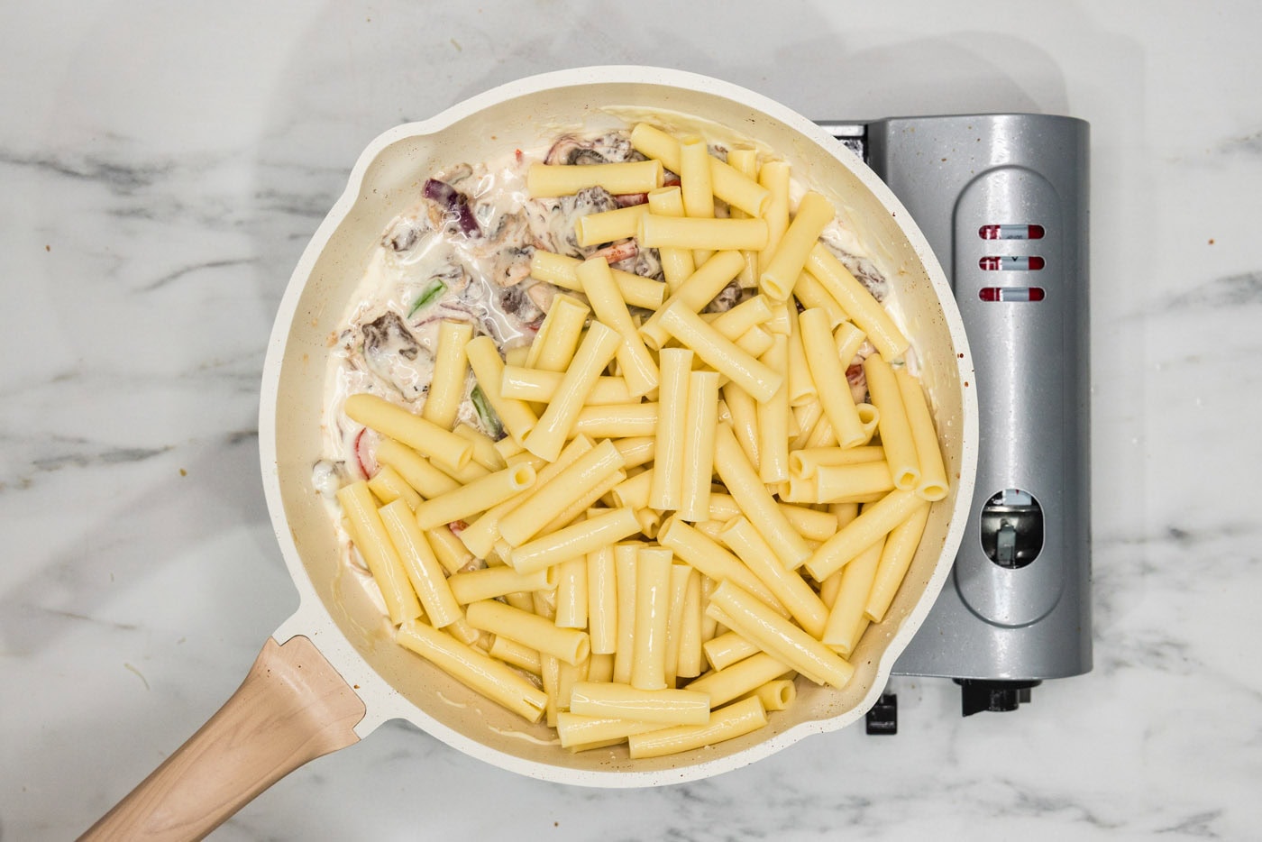 pasta added to skillet with meat, veggies, and cheese sauce