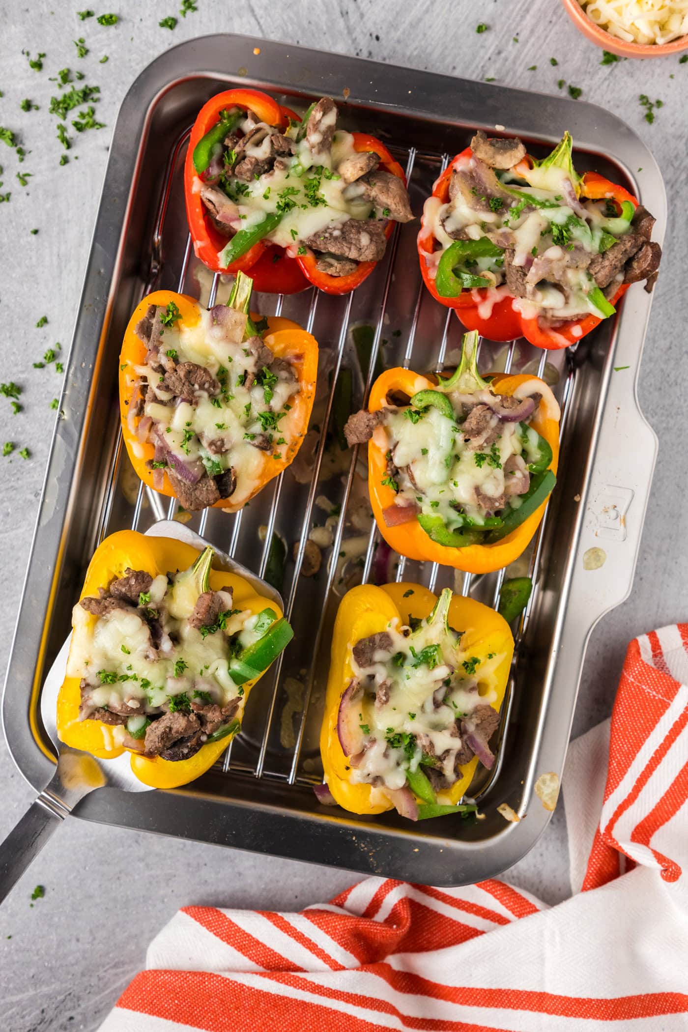 Spatula picking up a Philly Cheesesteak Stuffed Pepper off a pan of Philly Cheesesteak Stuffed Peppers