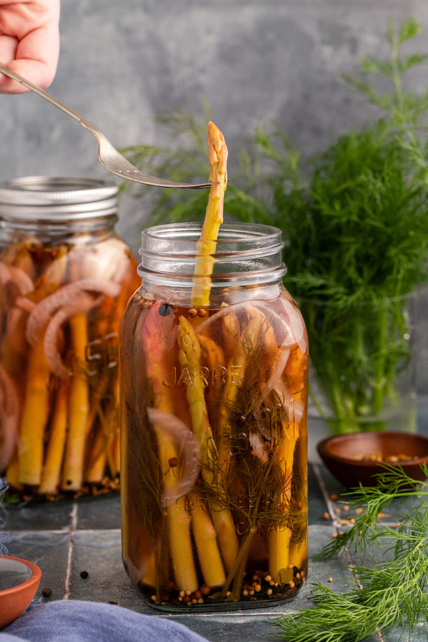 Piece of Pickled Asparagus being lifted out of the jar by a fork