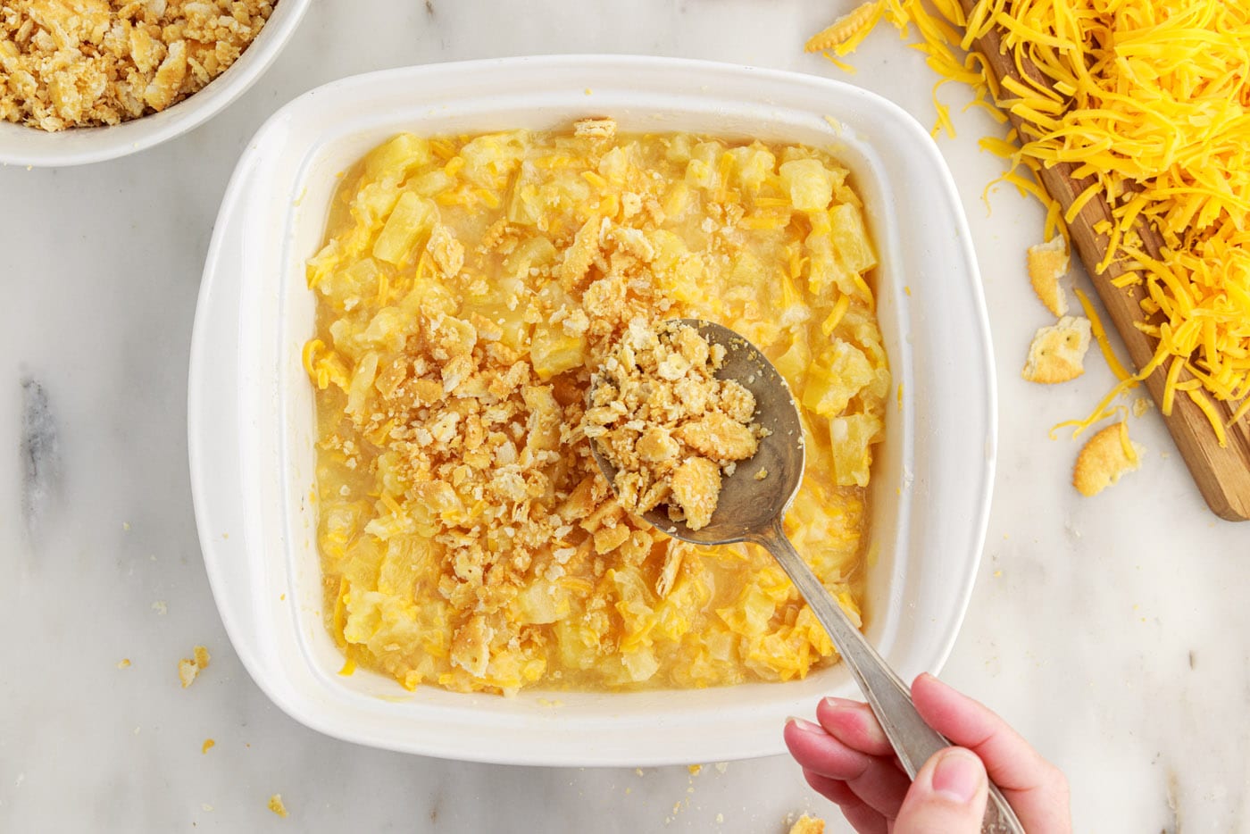 spreading ritz cracker topping over pineapple casserole