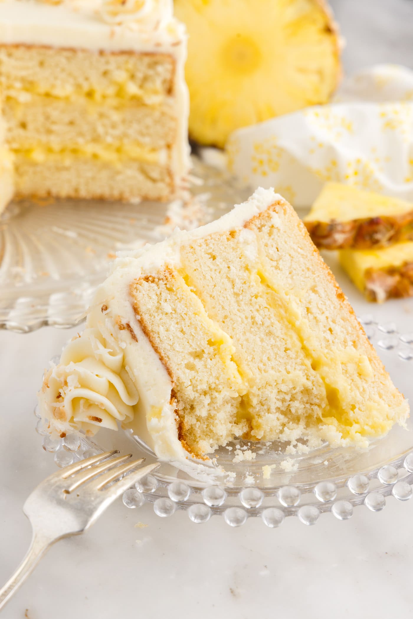Partially eaten slice of Pineapple Coconut Cake on a plate with a fork