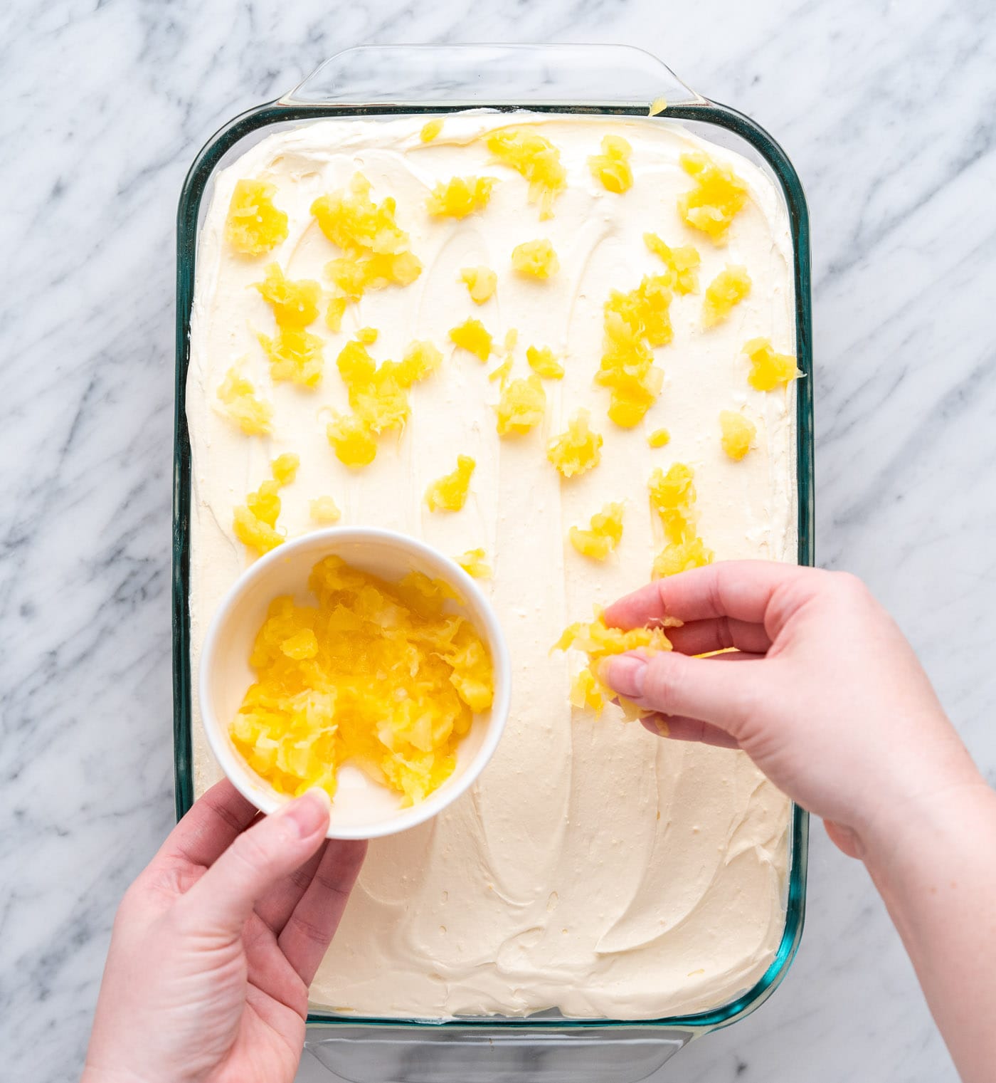 sprinkling pineapple on top of a cake