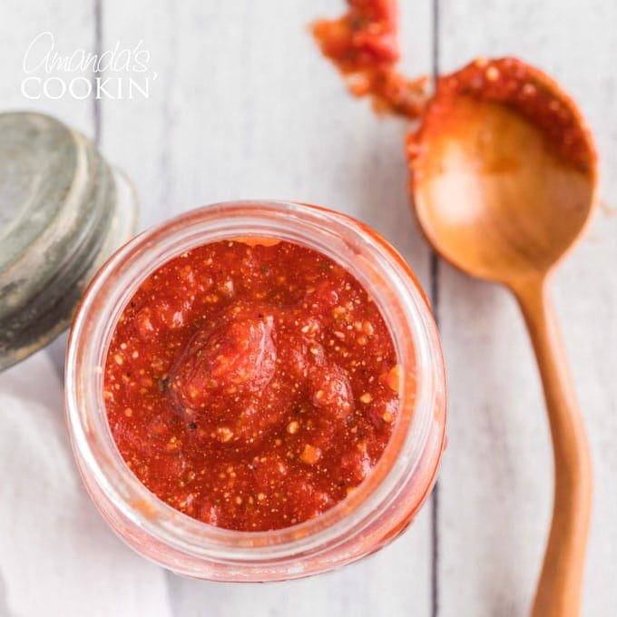 overhead view of jar of pizza sauce with spoon on the side