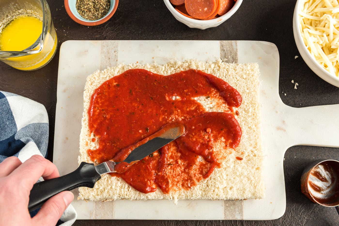 spreading pizza sauce over slider buns