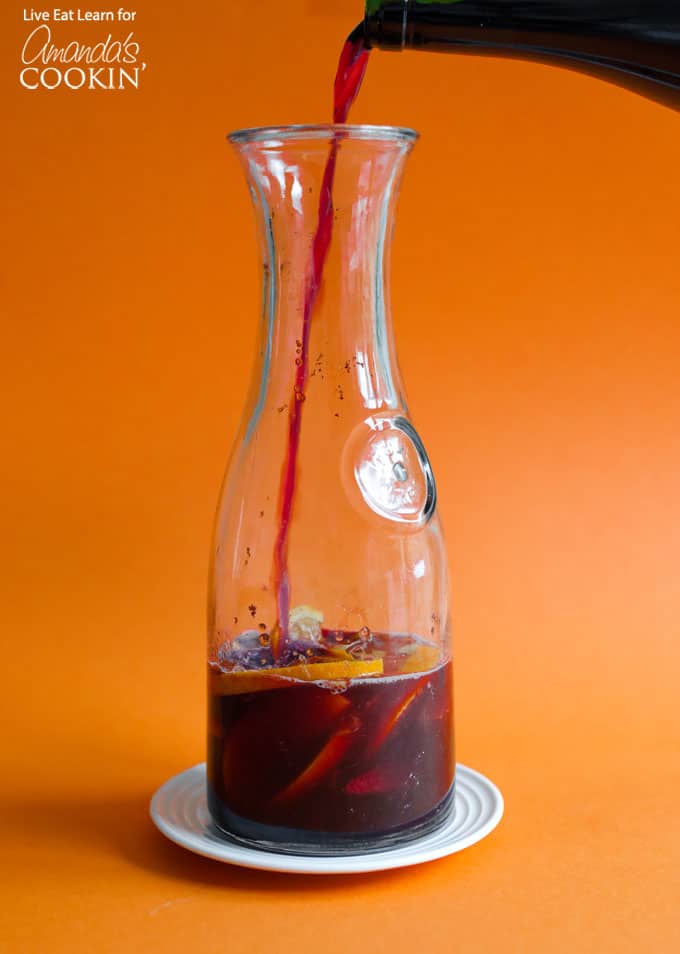 Pouring pomegranate sangria into pitcher