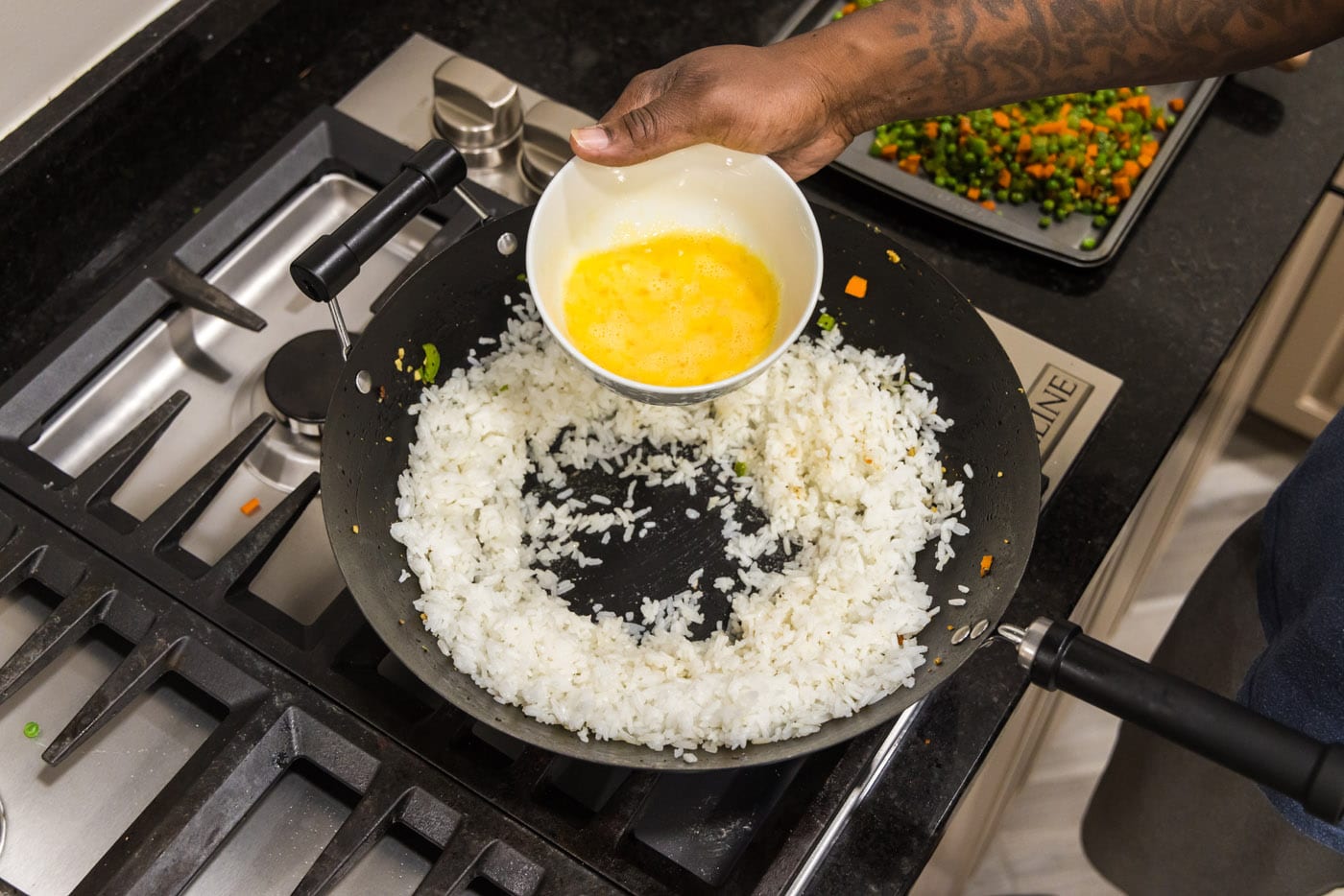 pouring whisked eggs into a well of rice