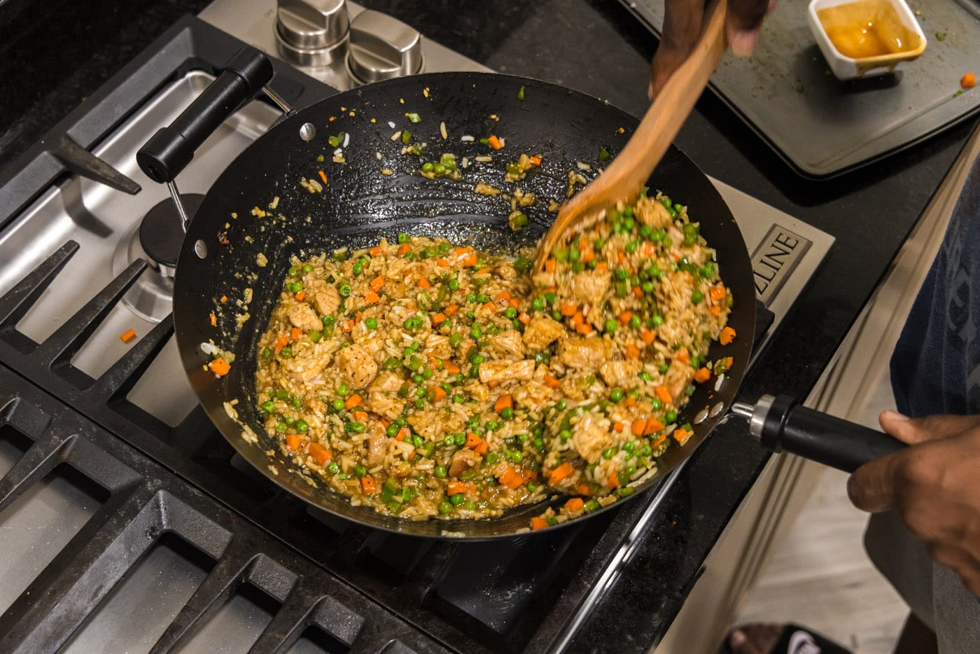 mixing pork fried rice in a wok with a wooden spoon