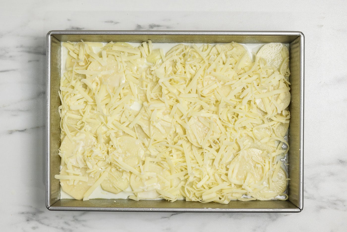 Layer of cheese on top of potatoes and sauce mixture
