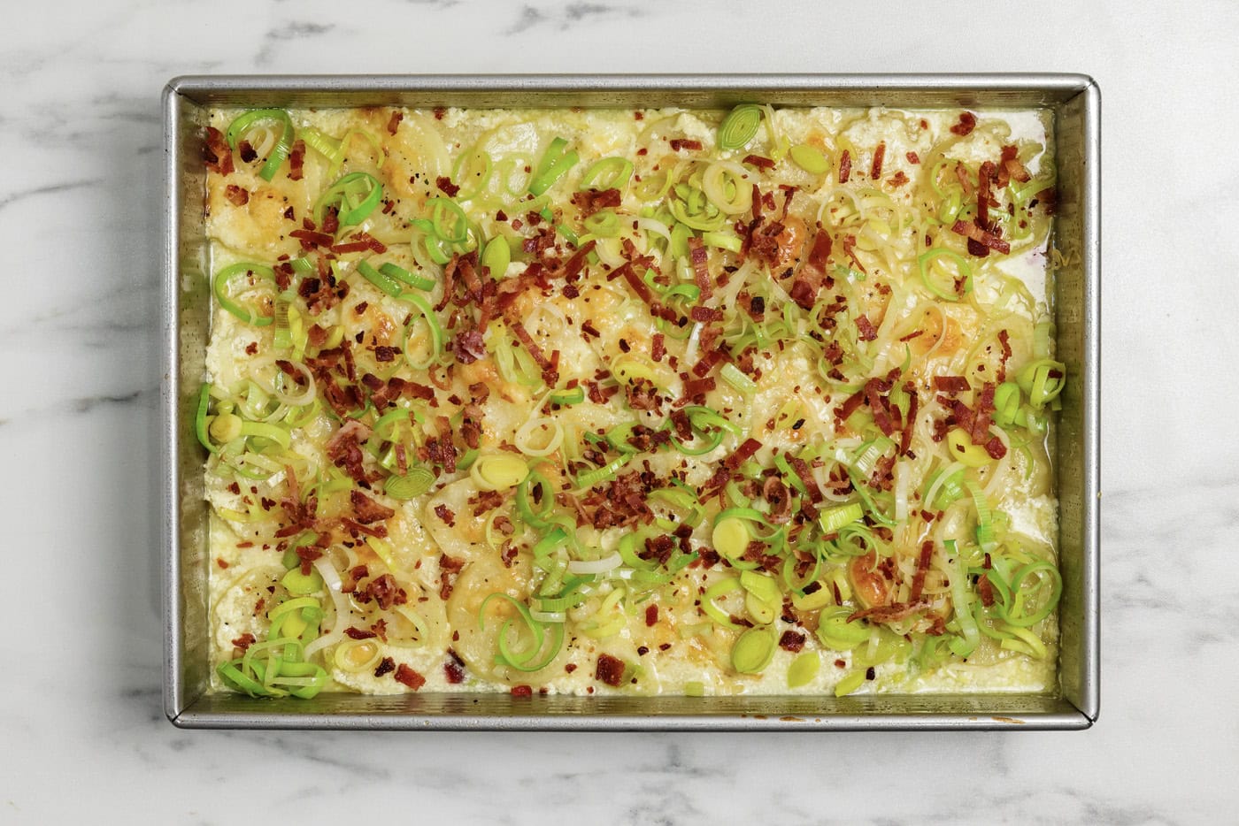 Sauteed leeks and crumbled cooked bacon on top of potatoes au gratin