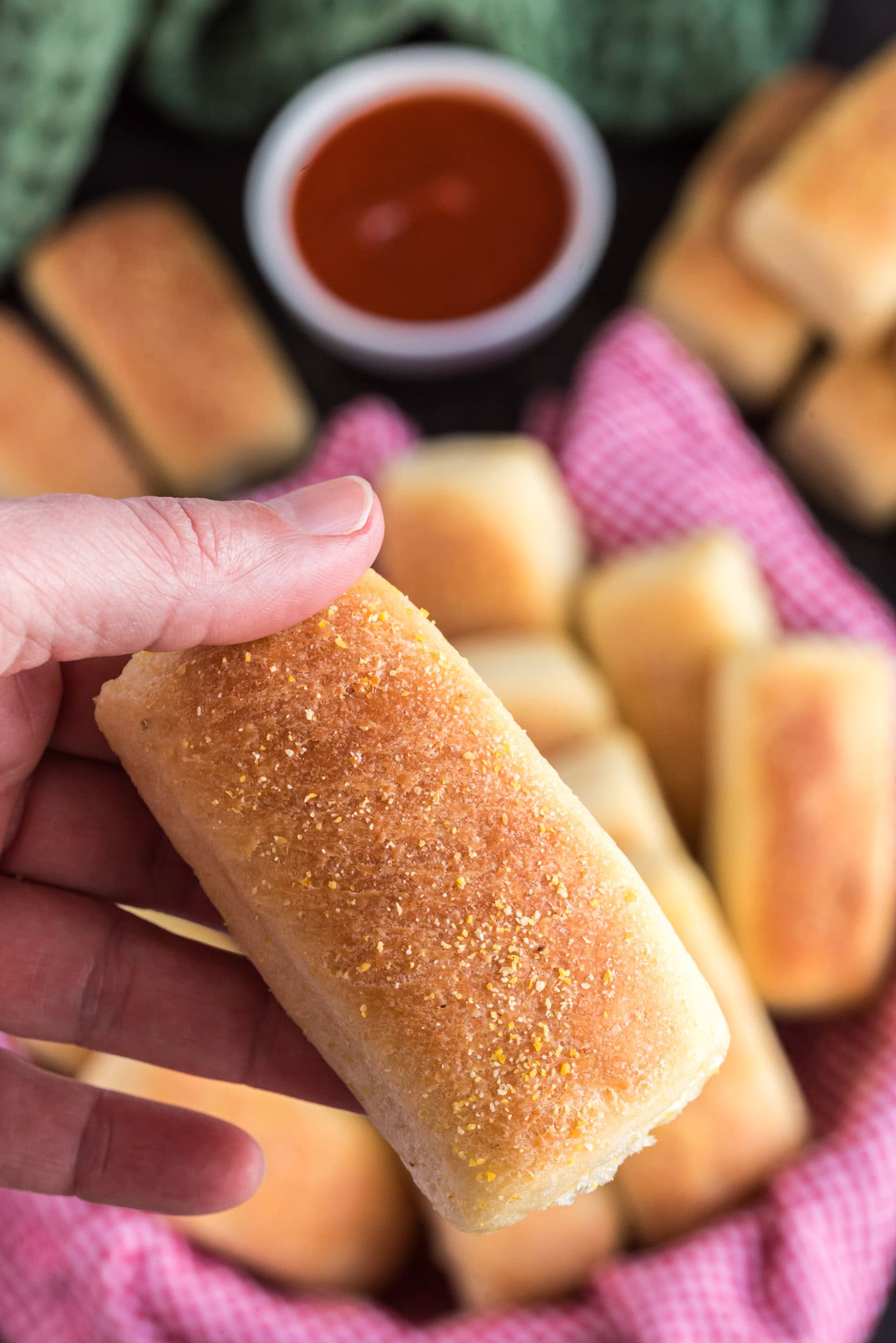 Hand holding up a Pull Apart Cornmeal Dinner Roll