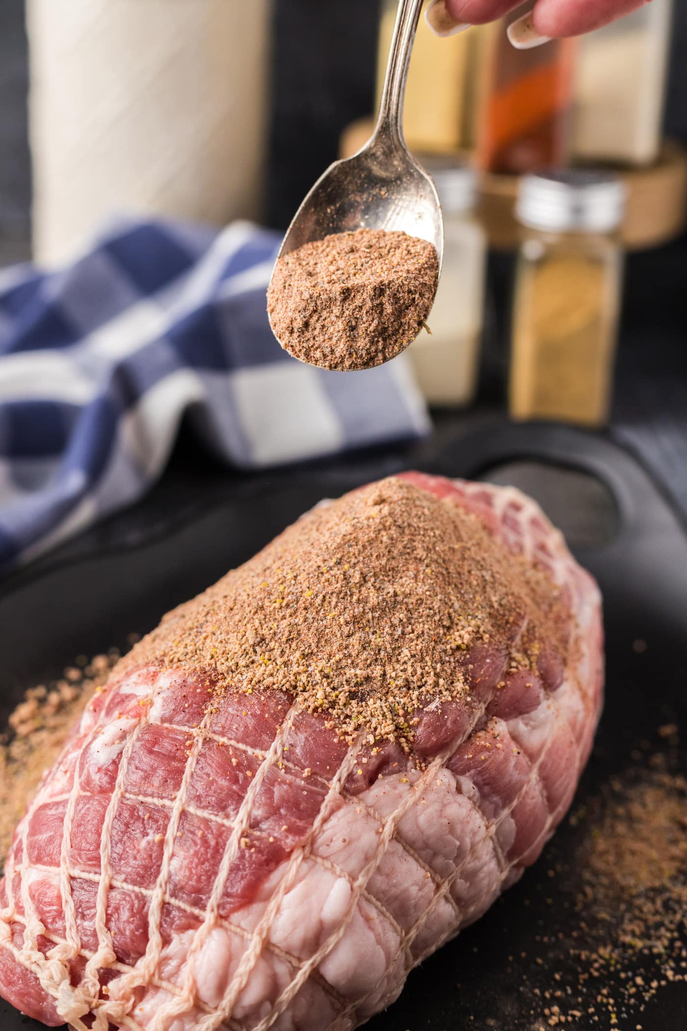 Spoonful of Pulled Pork Rub held above a boneless pork shoulder