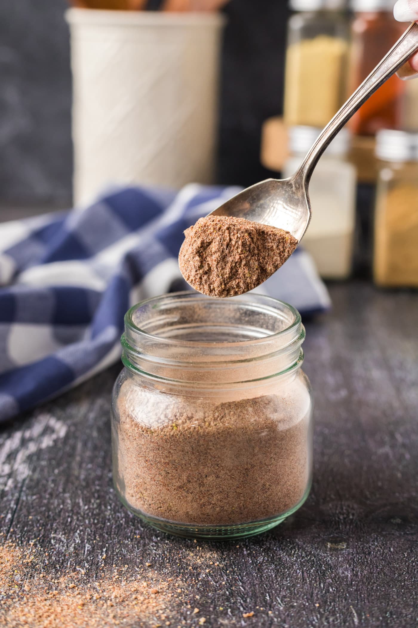Spoonful of Pulled Pork Rub held above a seasoning jar filled with rub