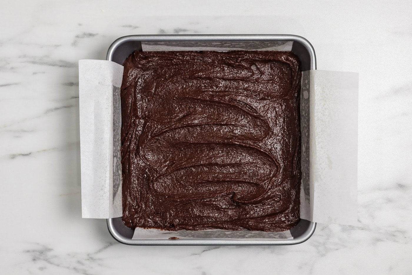 brownie batter spread in a 9x9 baking pan