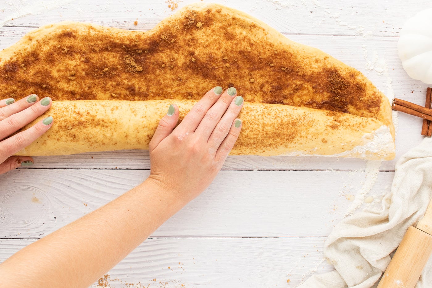 rolling cinnamon roll dough into log