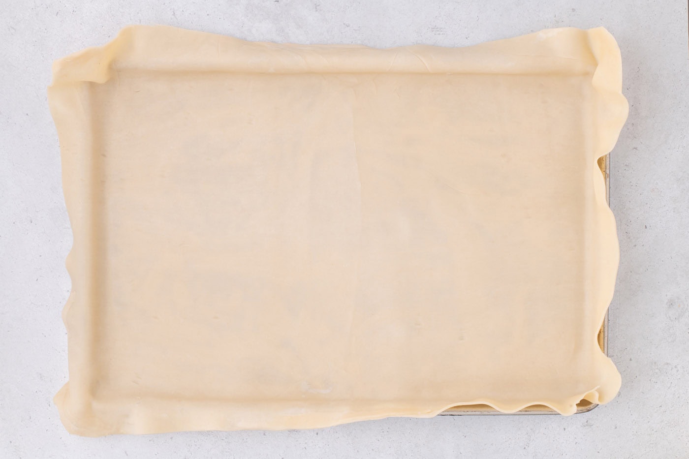 pie crust draping over a jelly roll pan