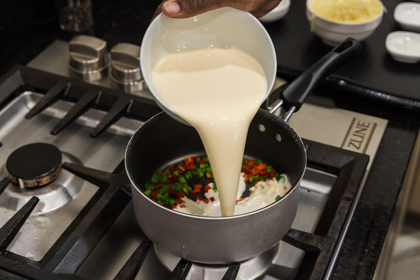 pouring evaporated milk into saucepan with peppers