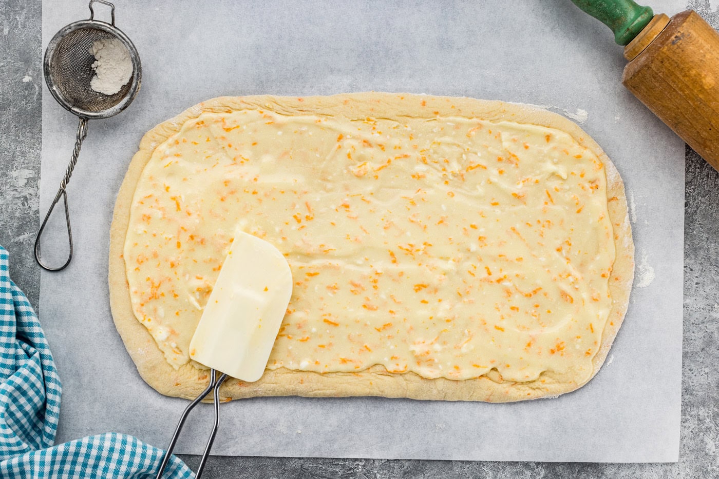 Spatula spread orange roll filling over dough