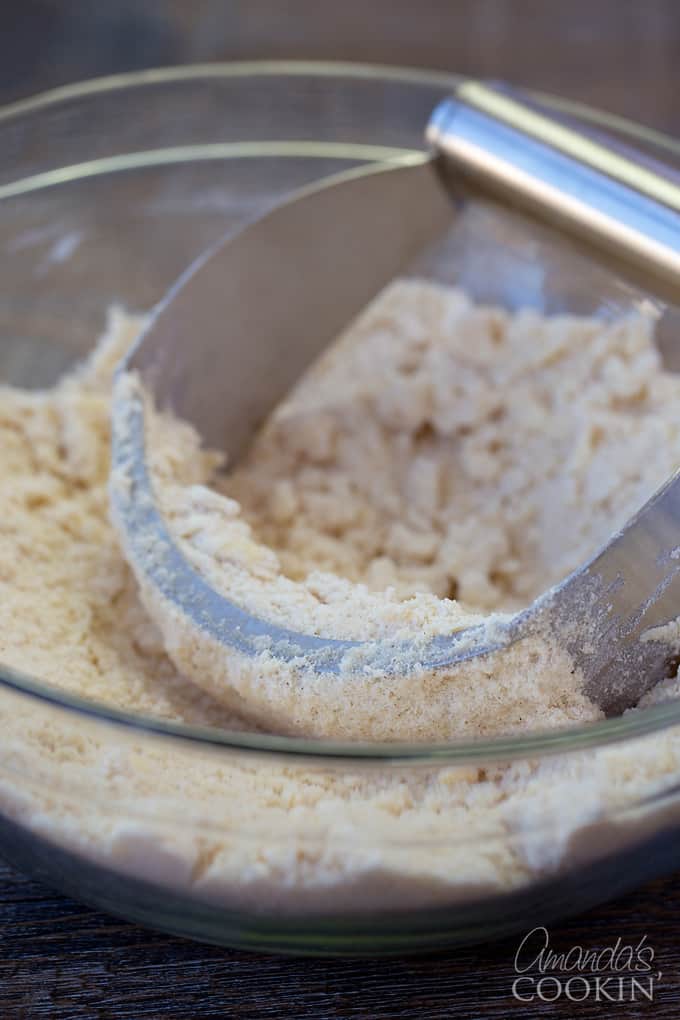 A clear bowl filled with the crumb mixture and a pastry blender.