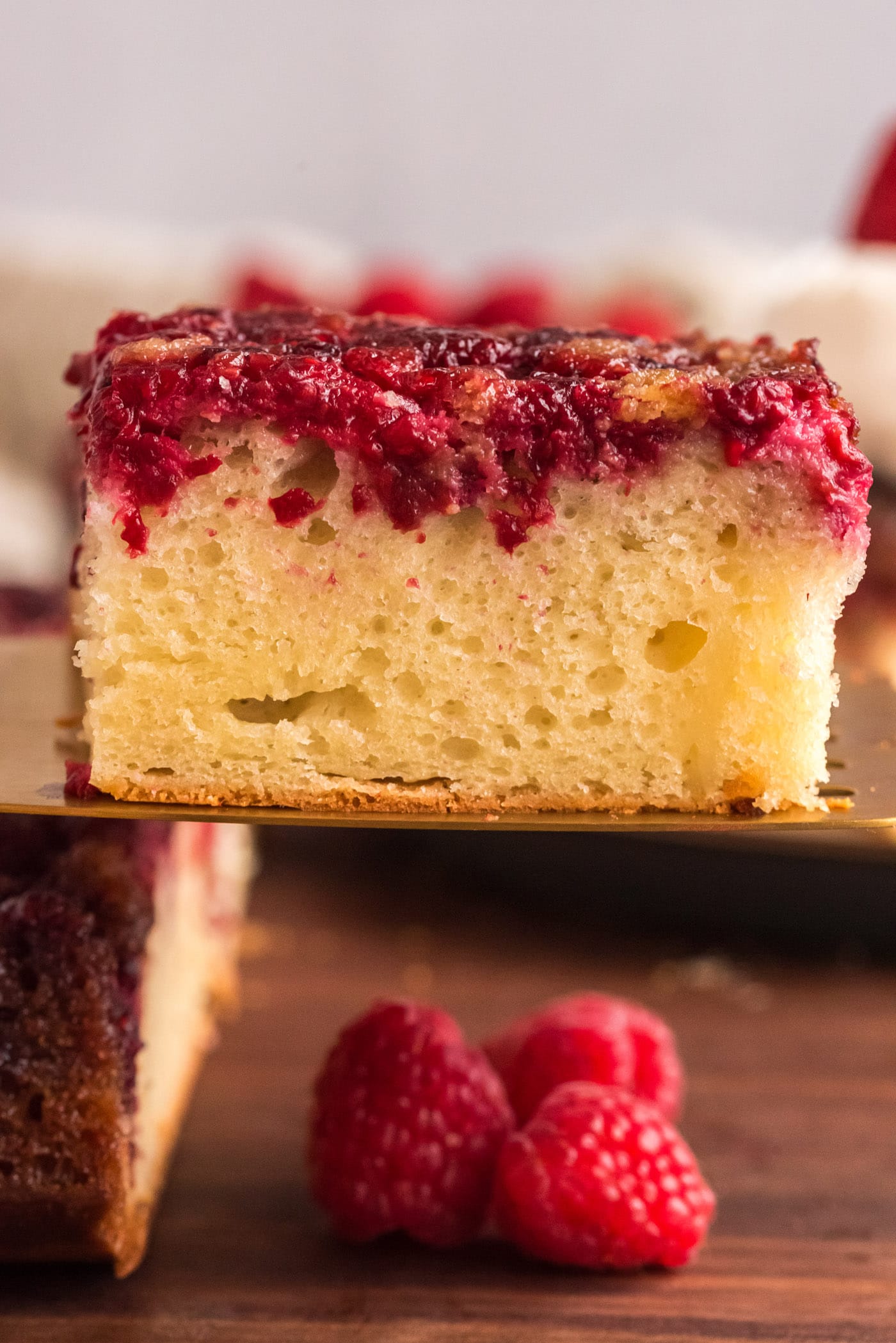Square of Raspberry Upside Down Cake lifted up on a spatula