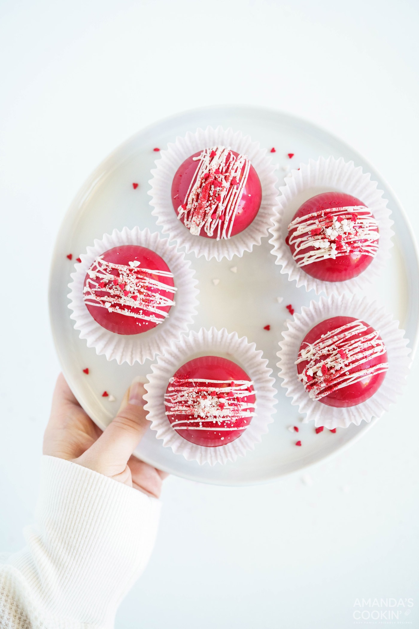 red velvet cocoa bombs in paper liners on plate