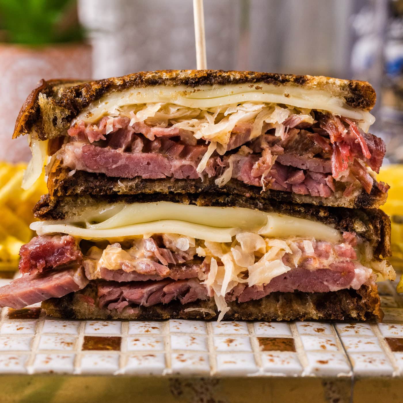 Close up photo of a Reuben Sandwich cut in half stacked on top of each other