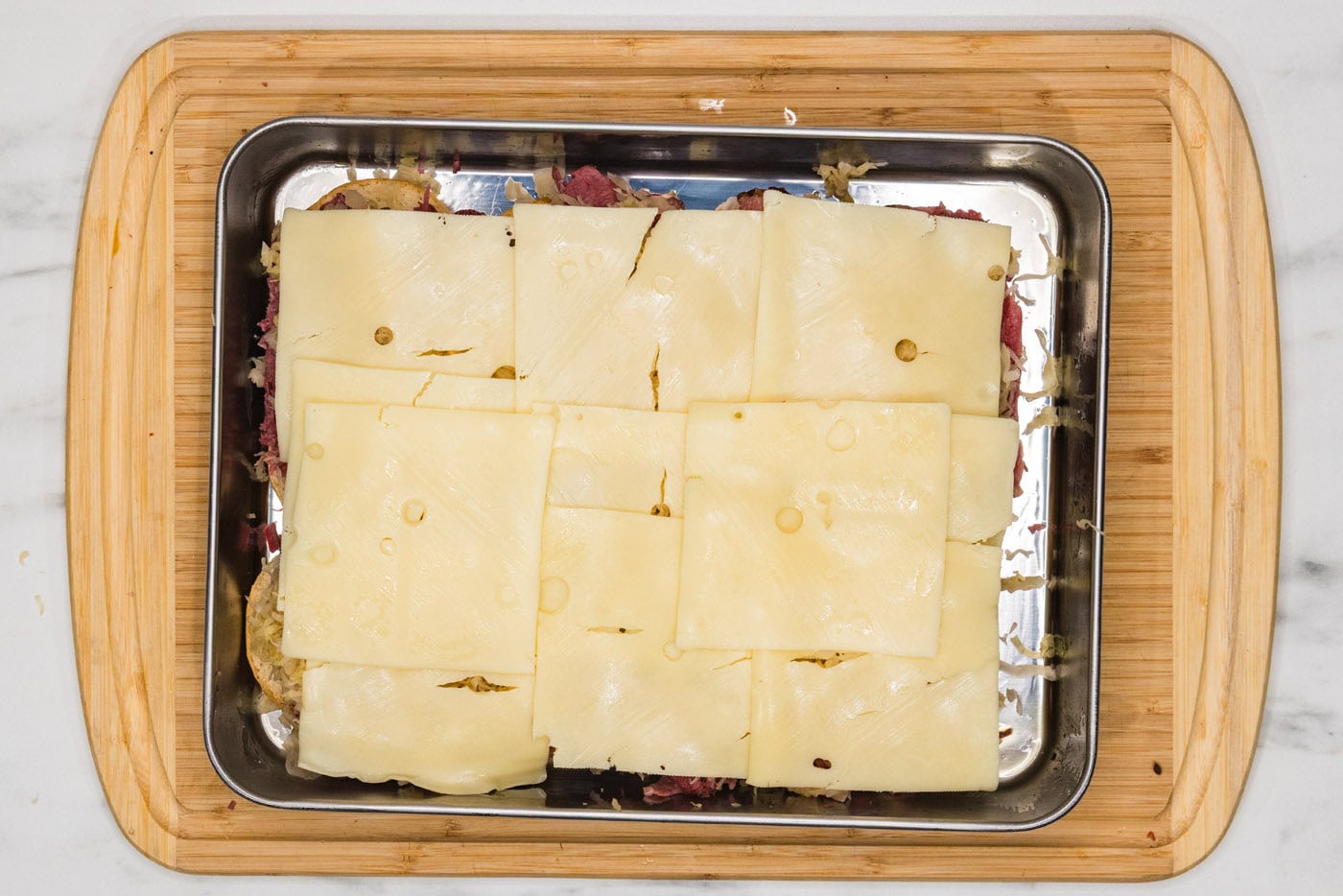 Swiss cheese on top of corned beef and sauerkrat