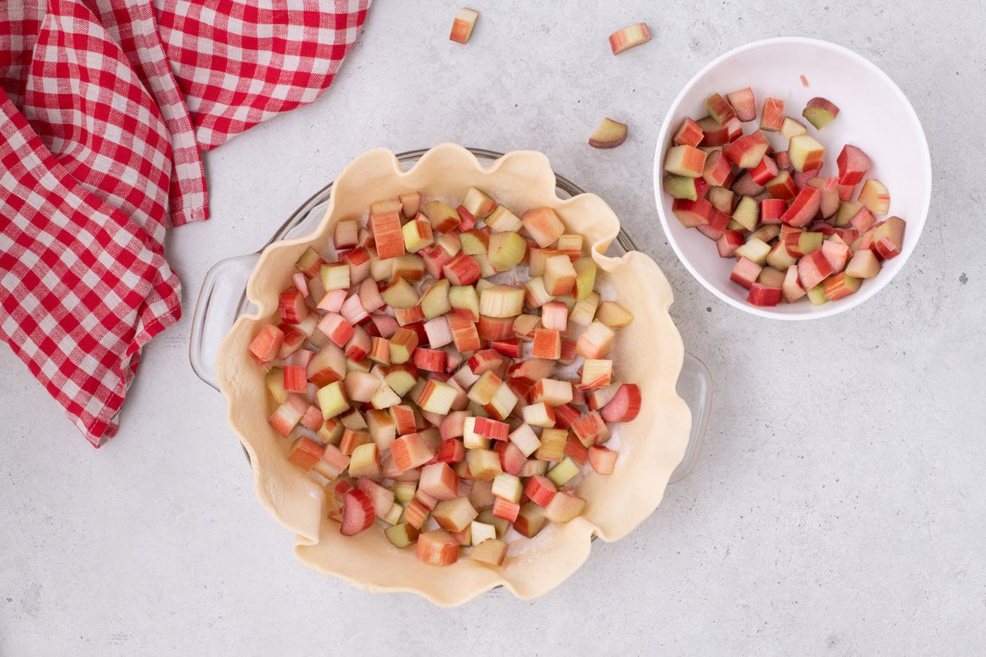 chopped rhubarb on top of sugar mixture in a pie crust