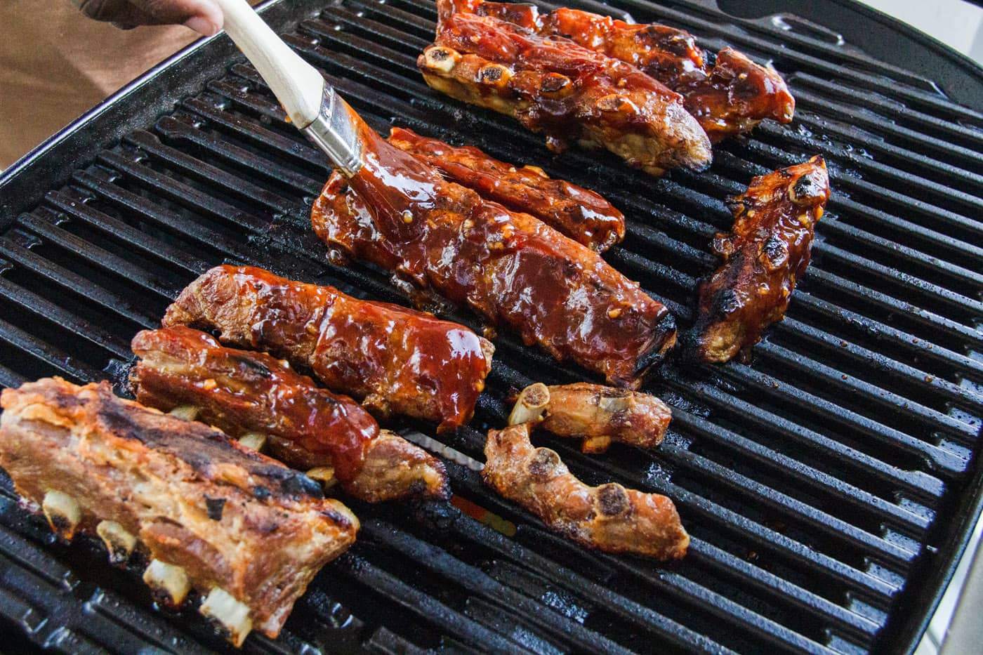 brushing rib tips with barbecue sauce