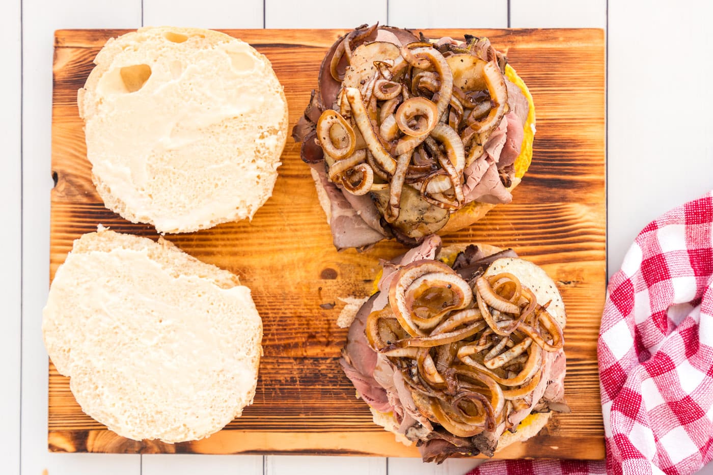 glazed onions and sliced potatoes on top of a roast beef sandwich