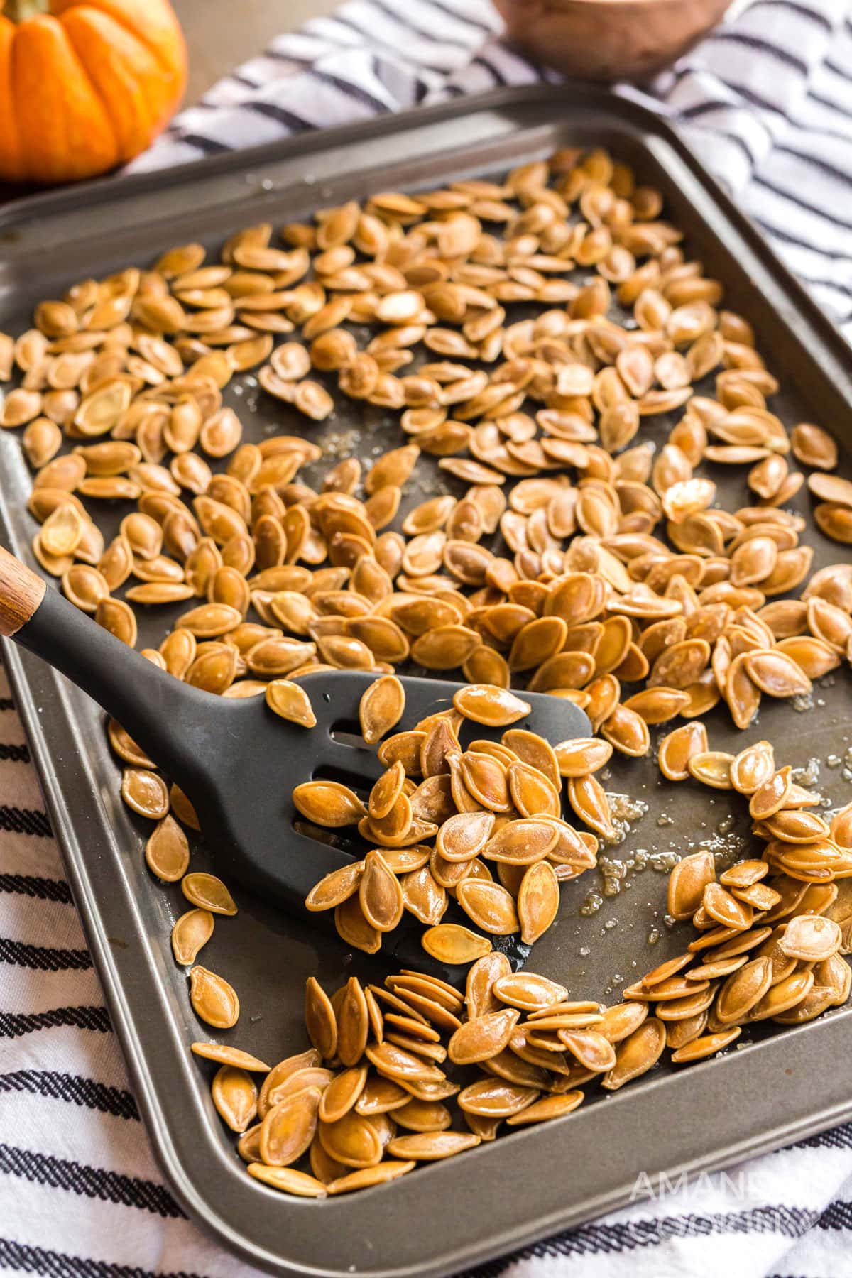 cookie sheet of roasted pumpkin seeds with a spatula