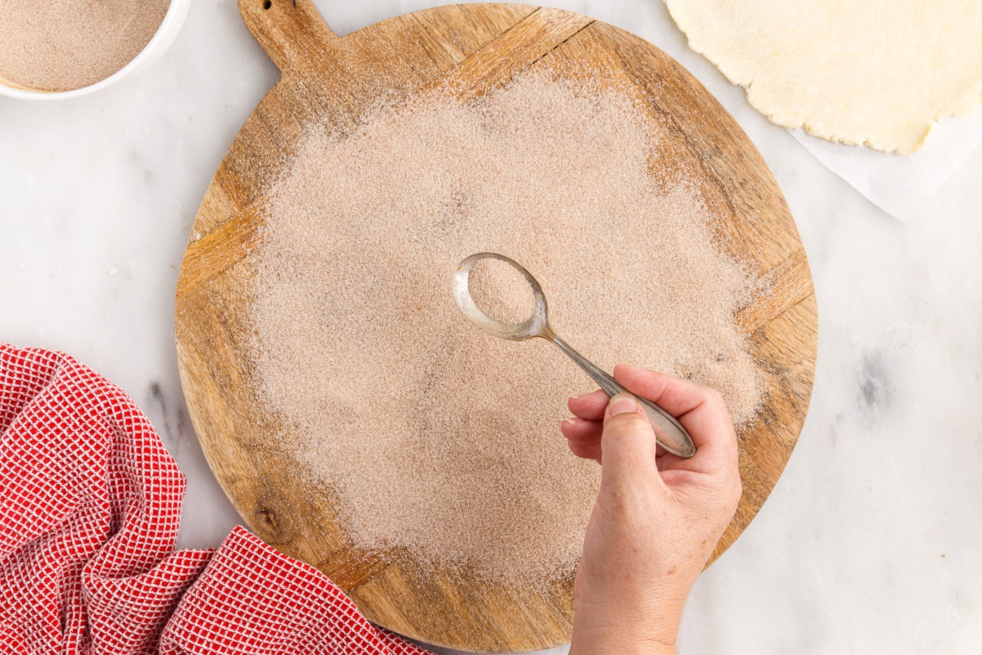 sprinkling cinnamon sugar over cutting board