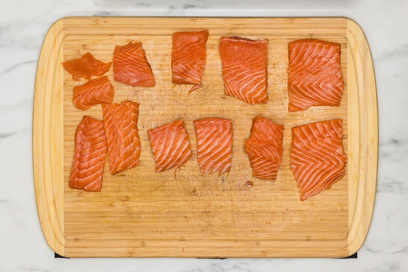 salmon cut into small portions on a cutting board