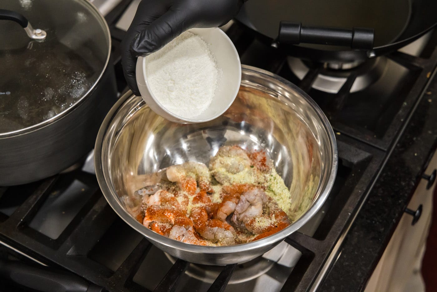 adding cornstarch to seasoned shrimp in a bowl