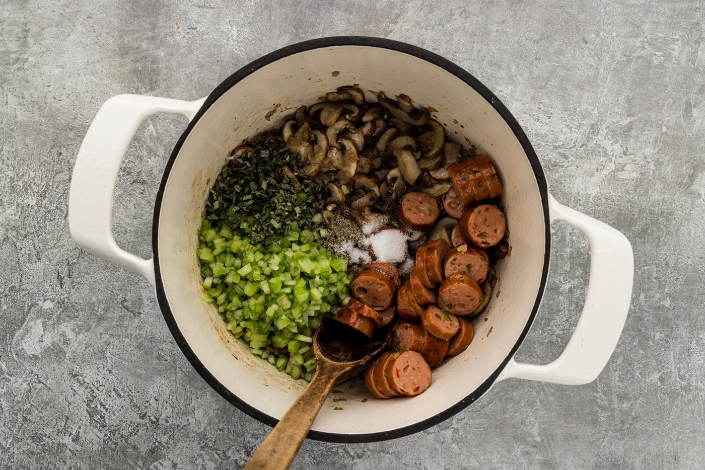 Browned mushrooms with sliced sausage, chopped celery, fresh sage, salt and pepper added to the pot