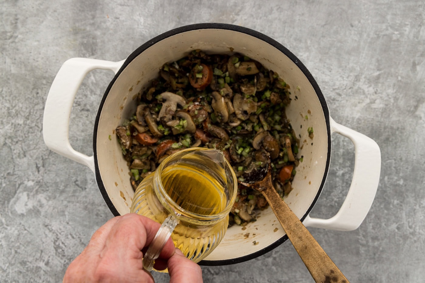 Pouring Chardonnay into the pot of sausage and mushrooms