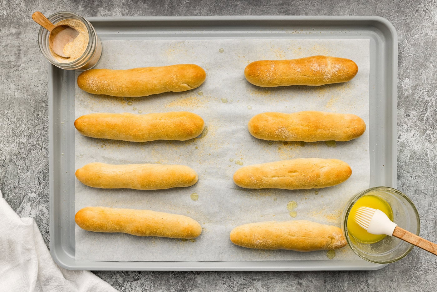 overhead of baked breadsticks on a baking sheet with butter and garlic salt