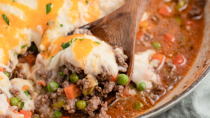 close up shepherds pie in a wooden spoon