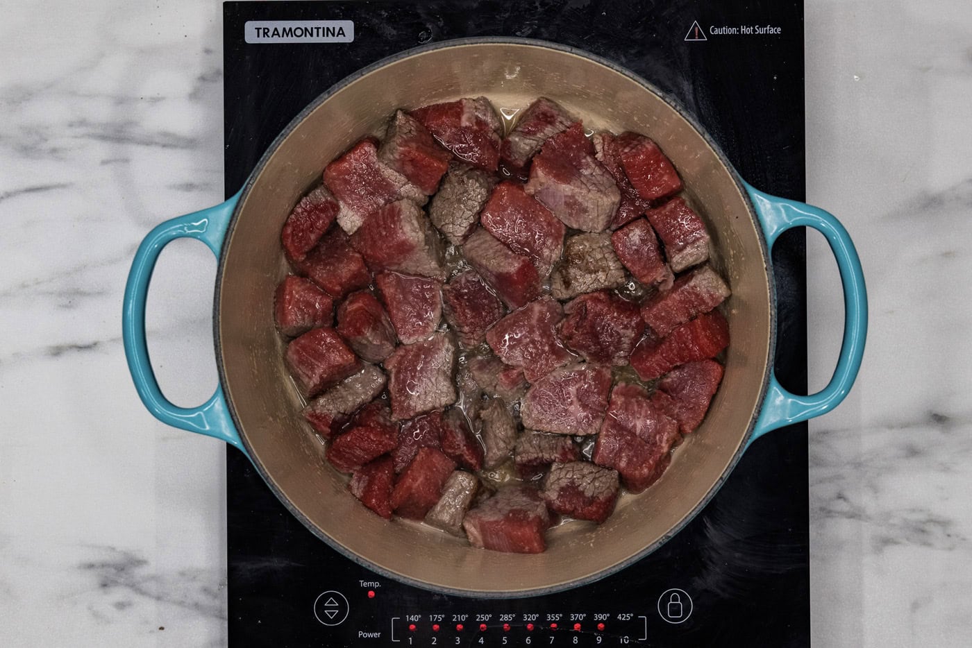 cubed beef short ribs searing in a dutch oven
