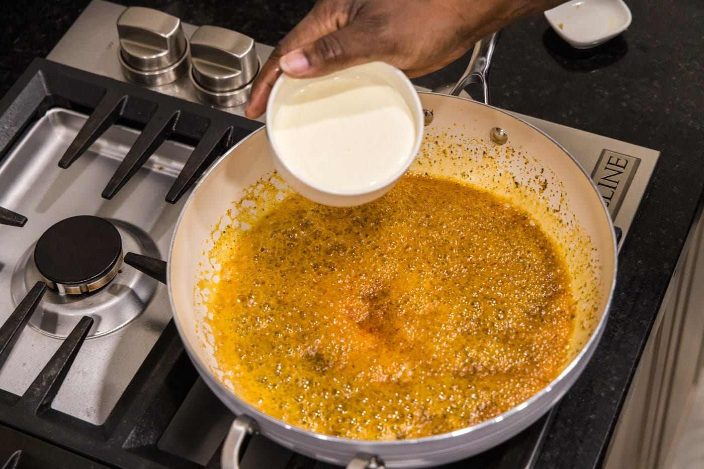 pouring heavy cream into alfredo sauce mixture