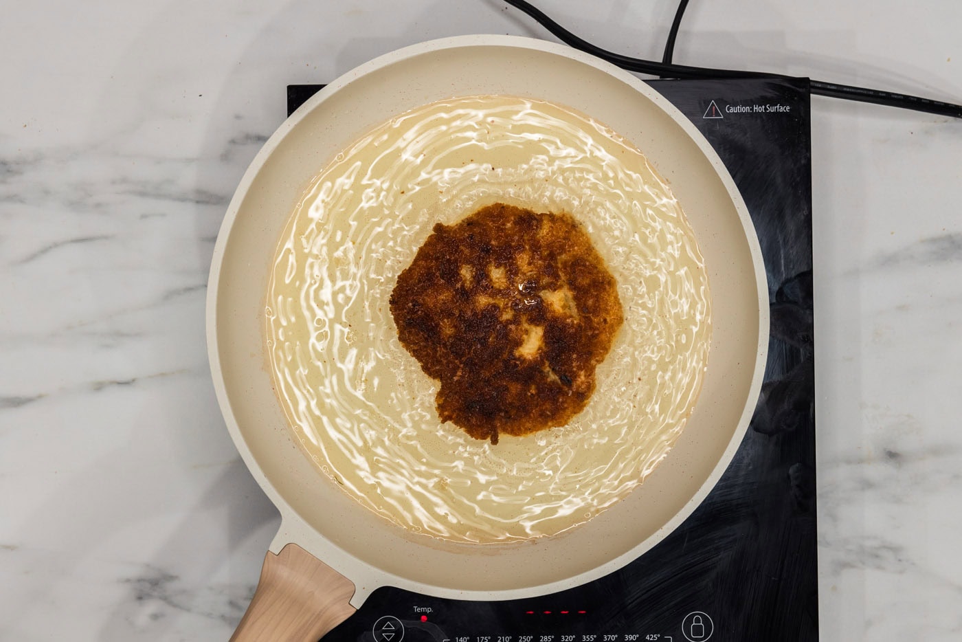 fried shrimp burger patty in a skillet of oil