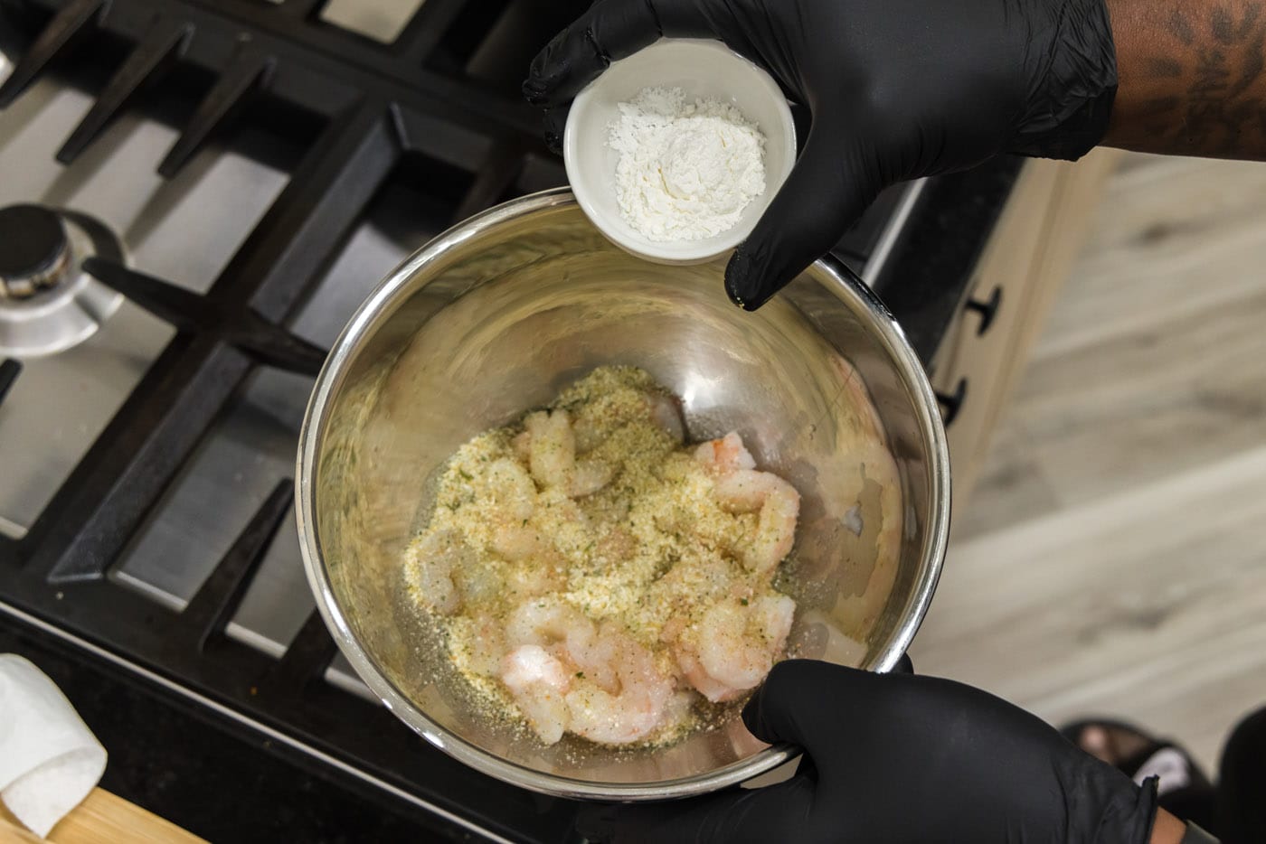 adding cornstarch to bowl with seasoned shrimp