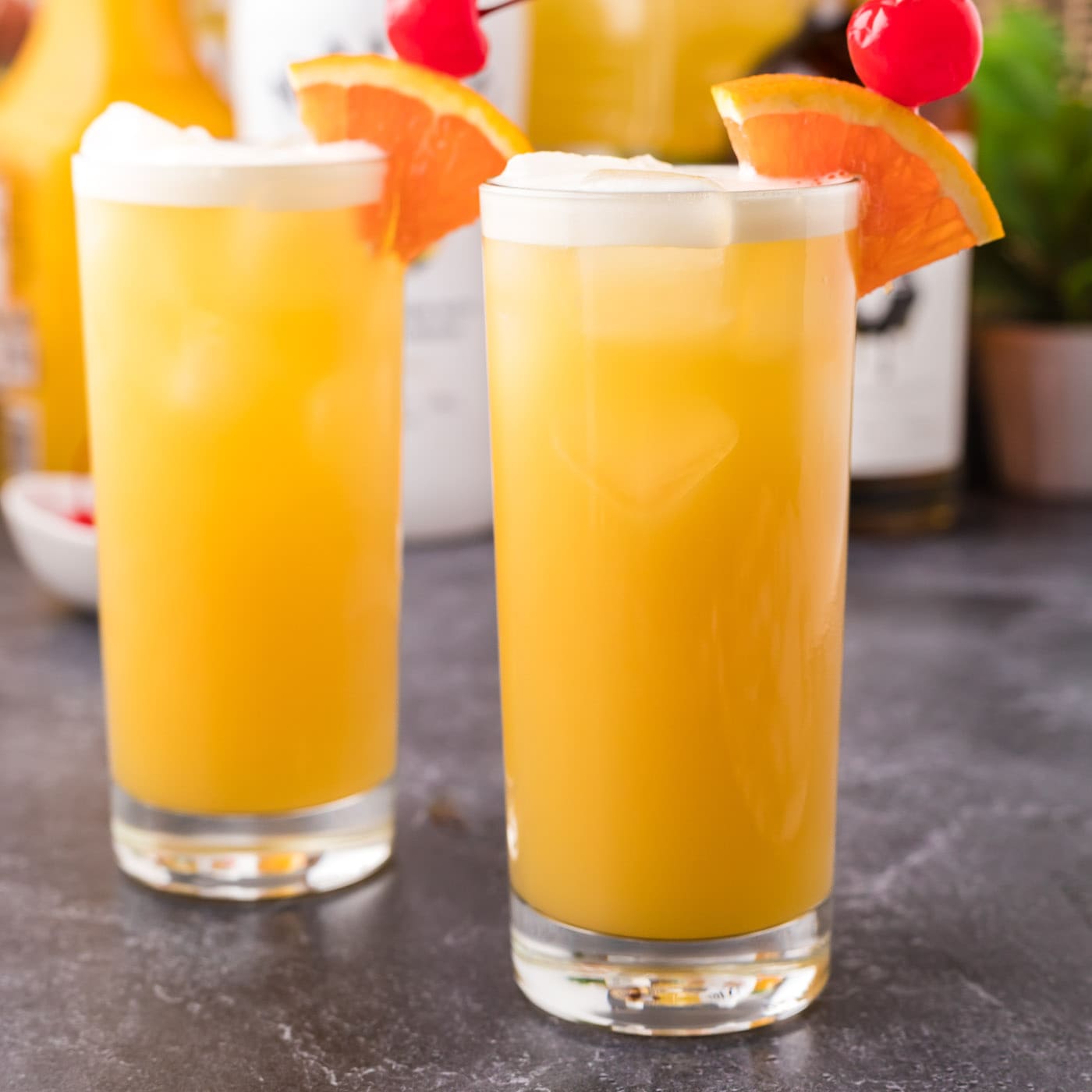 Two Skrew Loose Cocktails garnished with an orange slice and maraschino cherry
