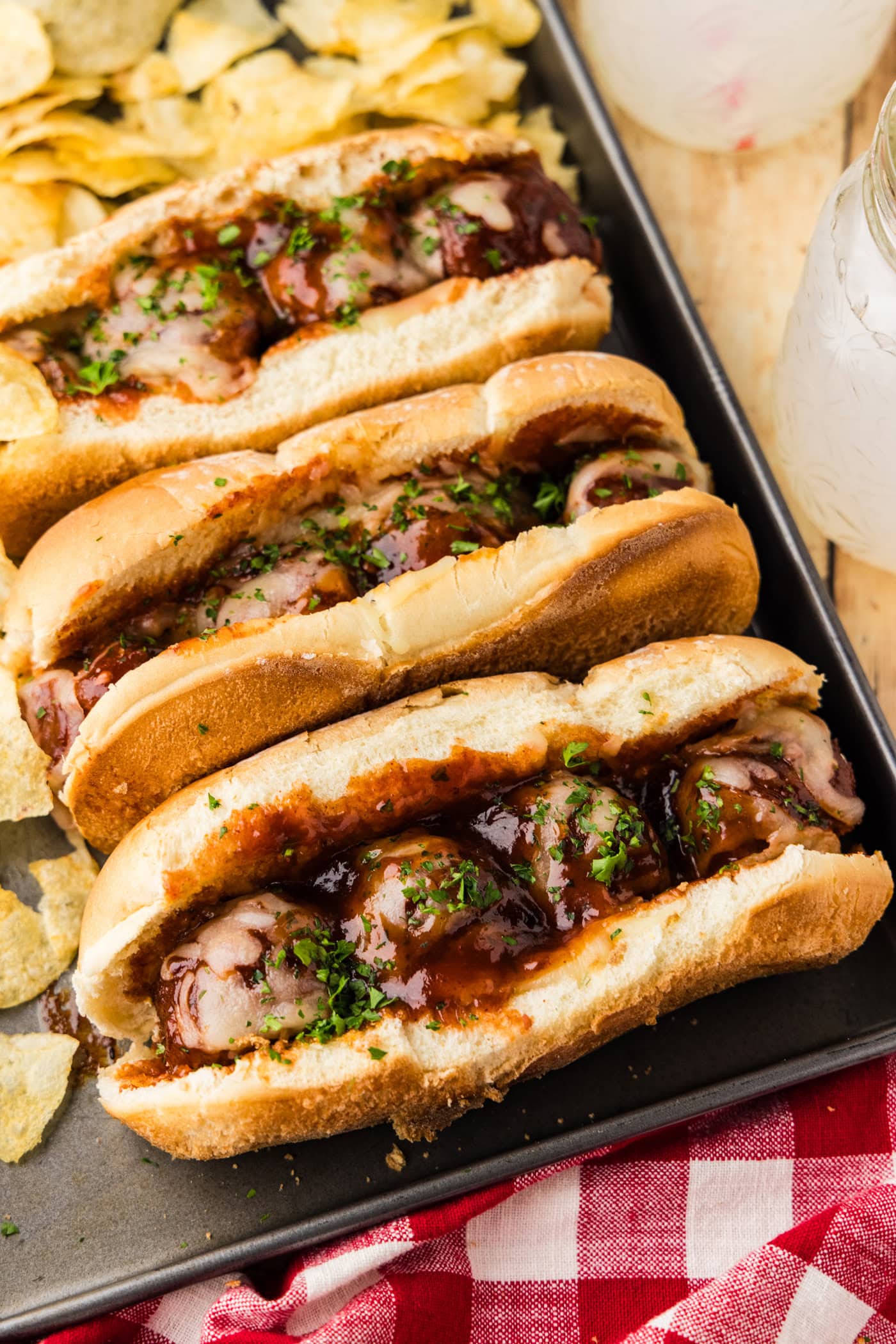 Slow Cooker BBQ Meatball Subs on a tray with chips