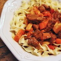 A close up photo of slow cooker Hungarian goulash and noodles in a bowl.